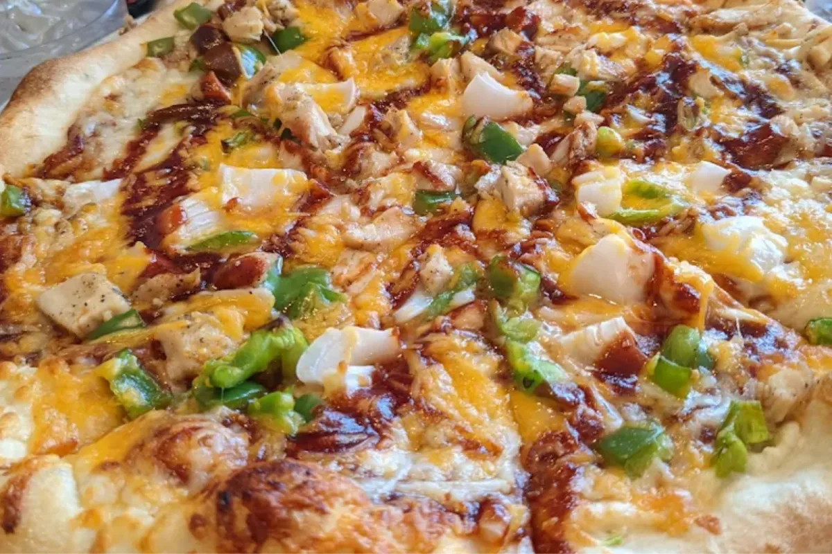 Loaded pizza with chicken, cheese, and fresh vegetable toppings